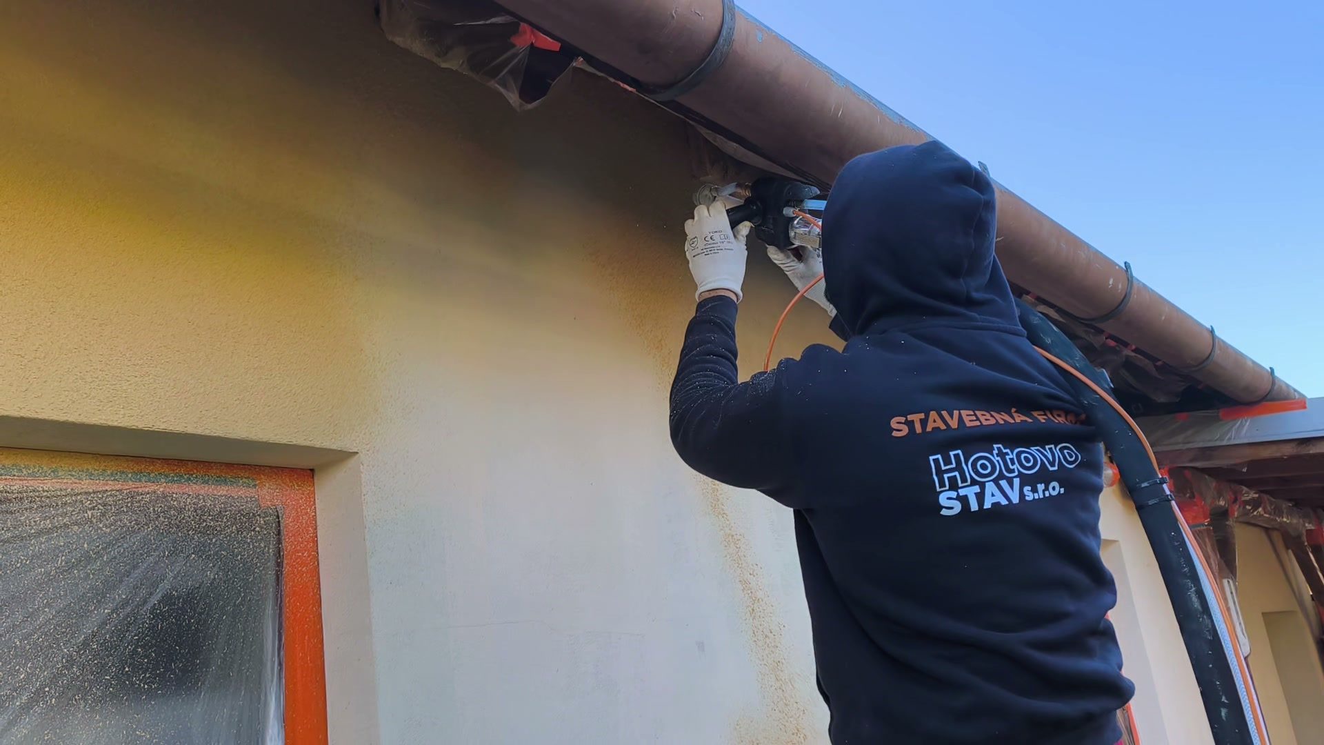 Pracovník firmy Hotovo STAV při stříkání fasády